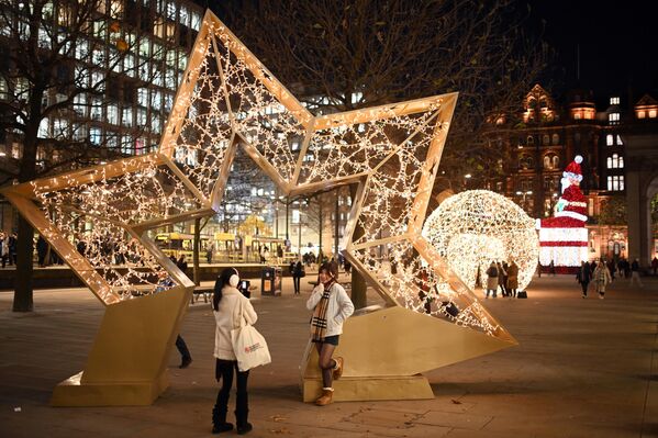 Người dân đi ngang qua những đồ trang trí Giáng Sinh được chiếu sáng ở Manchester, Vương quốc Anh - Sputnik Việt Nam