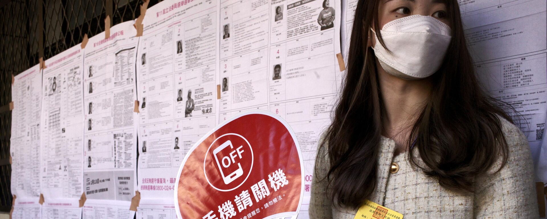 Một cô gái cầm chiếc quạt có tấm biển kêu gọi cử tri tắt điện thoại di động khi bỏ phiếu - Sputnik Việt Nam, 1920, 16.01.2024