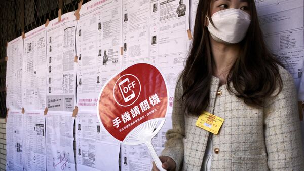 Một cô gái cầm chiếc quạt có tấm biển kêu gọi cử tri tắt điện thoại di động khi bỏ phiếu - Sputnik Việt Nam