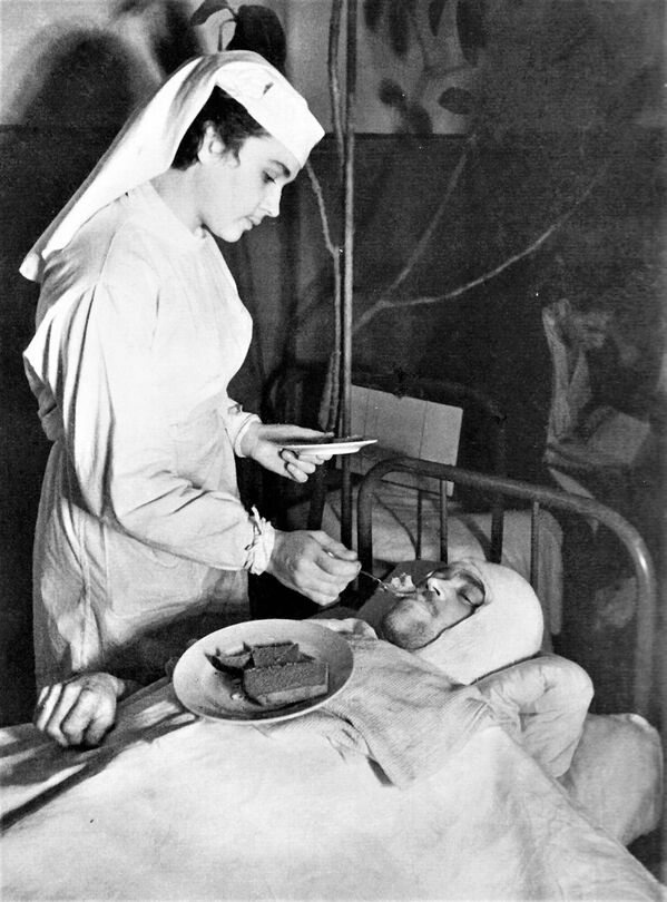 Bệnh viện Hải quân Leningrad: Nữ y tá Anna Yushkevich đang giúp một thương binh ăn - Sputnik Việt Nam
