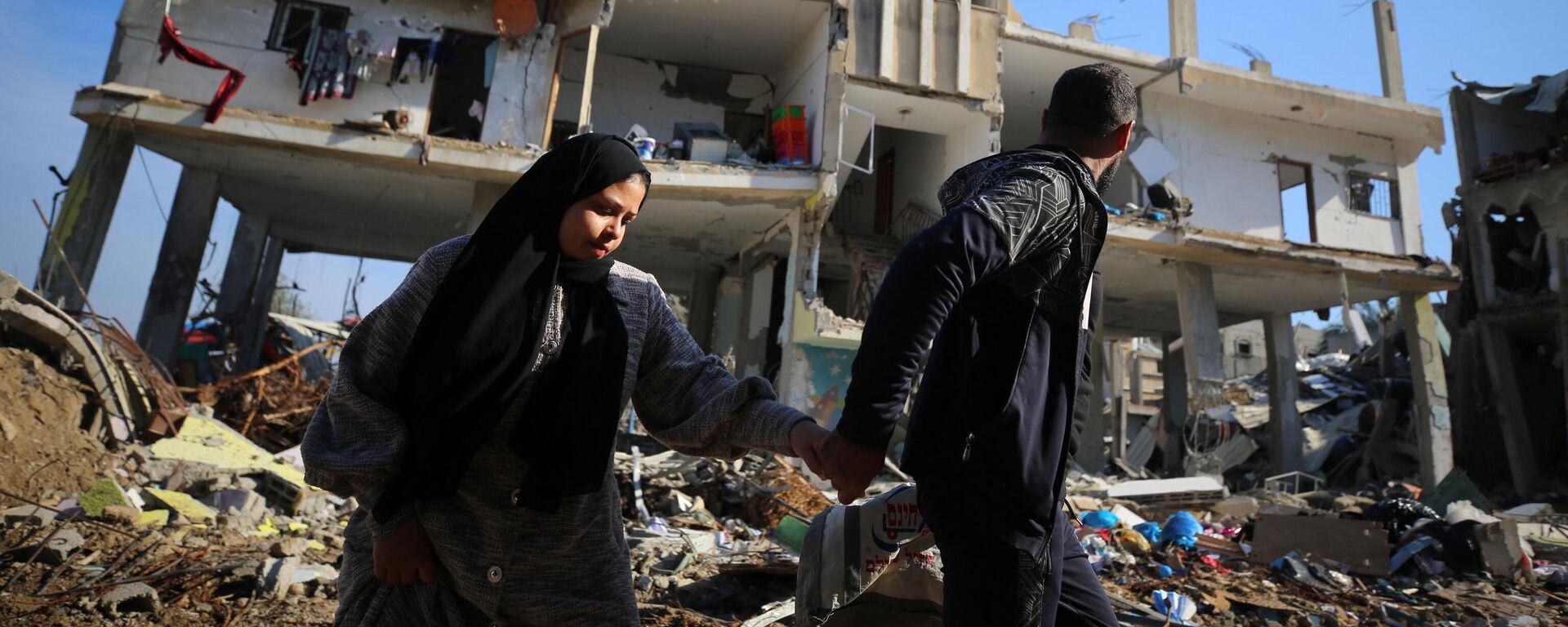 Người Palestine đi ngang qua một tòa nhà bị phá hủy trong trại tị nạn Al-Maghazi ở trung tâm Dải Gaza. - Sputnik Việt Nam, 1920, 08.02.2024