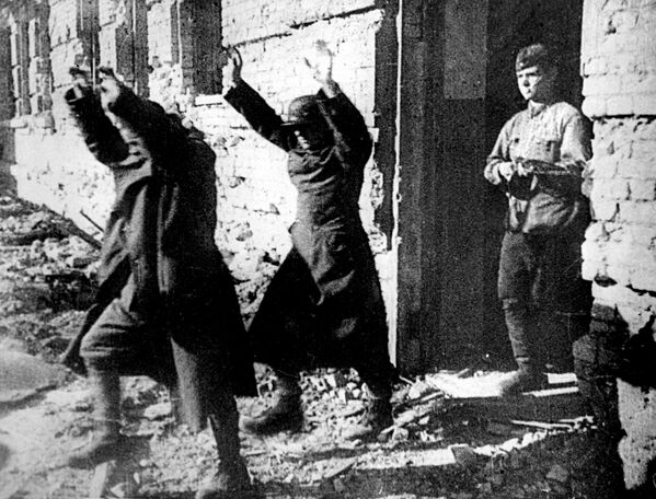 Hai người lính Đức Quốc xã với tay trên đầu được một người lính Nga dẫn ra - Sputnik Việt Nam