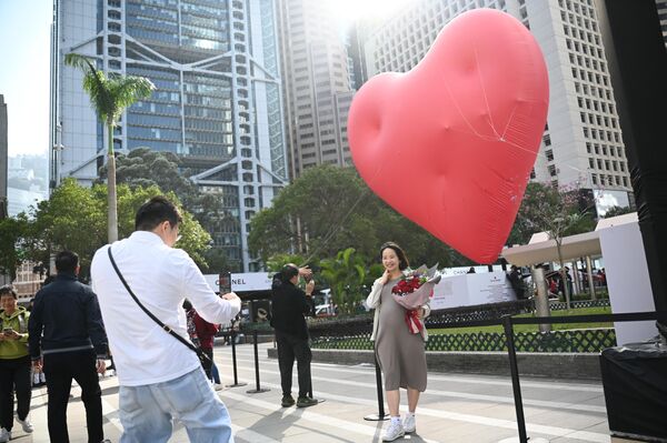 Người phụ nữ tạo dáng chụp ảnh trước trái tim khổng lồ trong Ngày lễ tình nhân ở Hồng Kông. - Sputnik Việt Nam