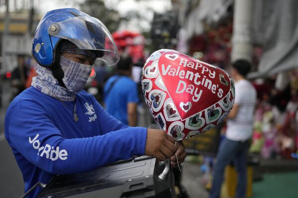 Người đàn ông buộc quả bóng bay vào xe máy của mình trong lễ kỷ niệm Ngày lễ tình nhân ở Manila, Philippines. - Sputnik Việt Nam