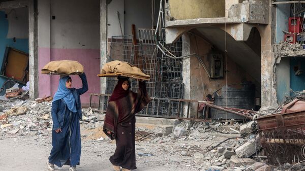 Phụ nữ đứng trước tòa nhà bị hư hại trong vụ đánh bom của Israel ở Rafah - Sputnik Việt Nam