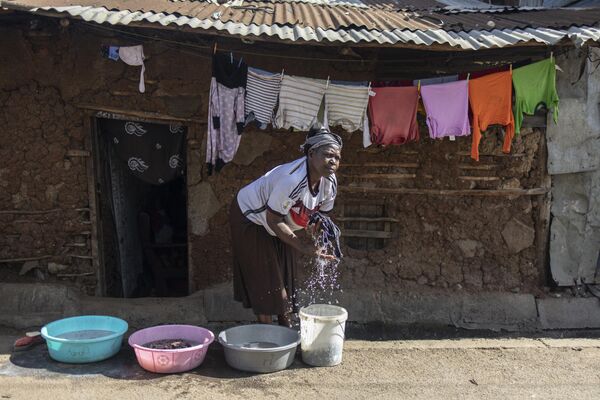 Người phụ nữ giặt quần áo bên ngoài nhà ở khu ổ chuột Mathare ở Nairobi - Sputnik Việt Nam