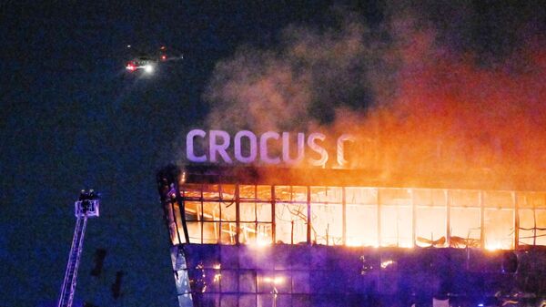 Lính cứu hỏa dập tắt mái nhà cháy của nhà hát Crocus City Hall, nơi vụ nổ súng xảy ra. - Sputnik Việt Nam