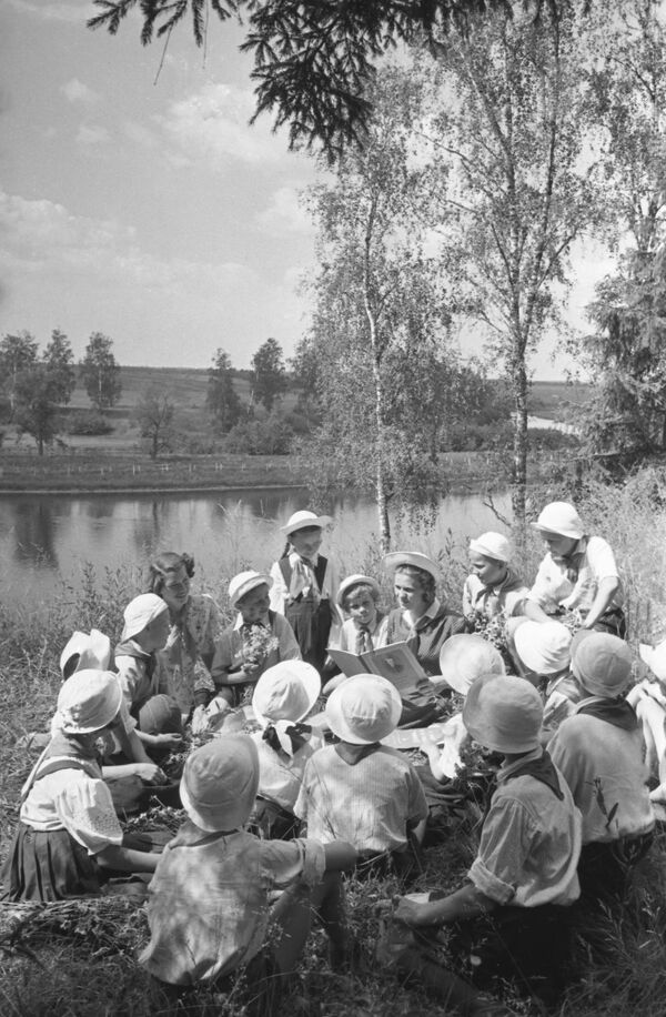 Trại hè thiếu nhi «Pakhra Đỏ» ở ngoại ô Matxcơva. Các đội viên tiền phong cùng hướng đạo sinh đang đọc sách bên bờ sông - Sputnik Việt Nam