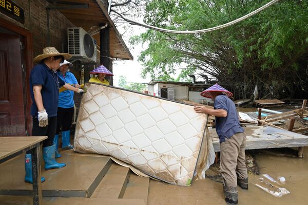 Công nhân dỡ tấm nệm ra khỏi phòng khách sạn sau khi mưa lớn làm ngập lụt địa bàn làng Sa Tân ở Thanh Viễn, phía bắc của tỉnh Quảng Đông, Trung Quốc - Sputnik Việt Nam