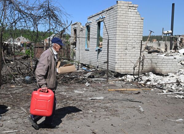 Người đàn ông cạnh tòa nhà dân cư bị hư hại do pháo kích ở làng Liman 1, tỉnh Kharkov - Sputnik Việt Nam