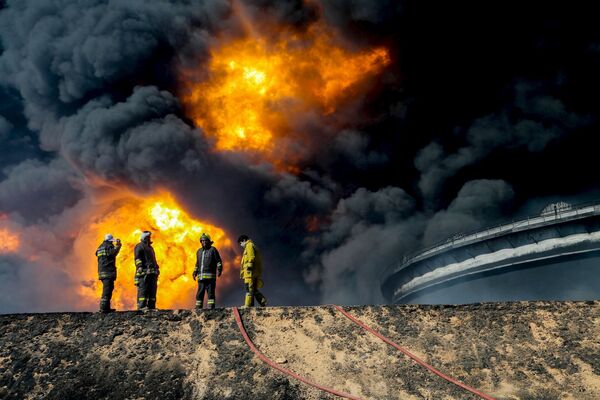 Nhân viên cứu hỏa trên nền kho chứa dầu bốc cháy tại thành phố Ras Lanuf ở Libya - Sputnik Việt Nam