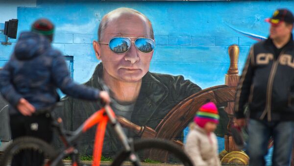 Người đi bộ trước chân dung Tổng thống Nga Putin trên tường một tòa nhà ở Yalta, Crưm. - Sputnik Việt Nam
