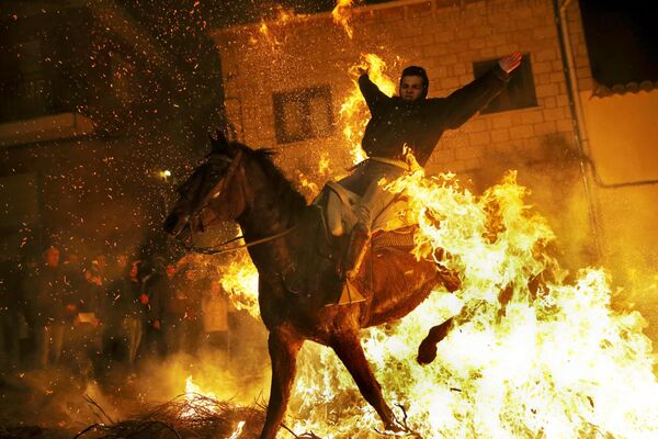 Người đàn ông cưỡi ngựa vượt qua ngọn lửa thanh tẩy trong ngày hội Thánh Anthony. - Sputnik Việt Nam
