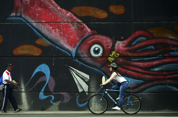 Thiếu nữ Colombia đi xe đạp ngàng qua bức graffiti ở thành phố Medellin - Sputnik Việt Nam