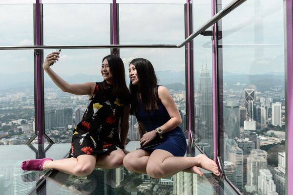 Cô gái Malaysia chụp ảnh trong Sky Box trên nền toàn cảnh từ  tháp truyền hình Kuala Lumpur - Sputnik Việt Nam