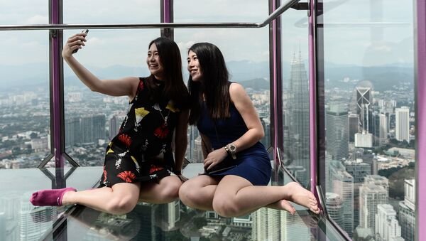 Cô gái Malaysia chụp ảnh trong Sky Box trên nền toàn cảnh từ  tháp truyền hình Kuala Lumpur - Sputnik Việt Nam