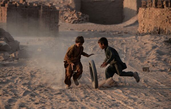 Các trẻ em Afghanistan chơi với bánh xe trên con đường cát bụi ở ngoại ô Jalalabad - Sputnik Việt Nam