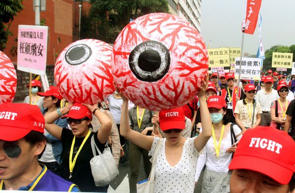 Những người tham gia phong trào công đoàn Đài Loan cầm trong tay mô hình con mắt nhân tạo tấy đỏ tượng trưng cho sự mệt mỏi của công nhân - Sputnik Việt Nam