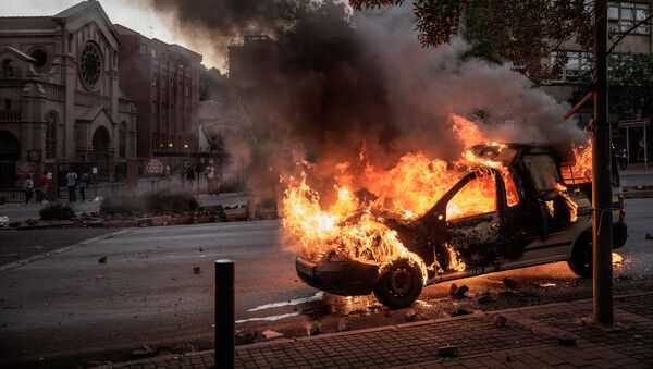 Горящий автомобиль в Йоханнесбурге, где прошли студенческие протесты - Sputnik Việt Nam