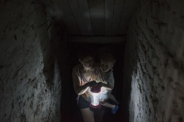 Người phụ nữ với đứa trẻ trốn trong tầng hầm ngôi nhà  của họ ở Gorlovka - Sputnik Việt Nam