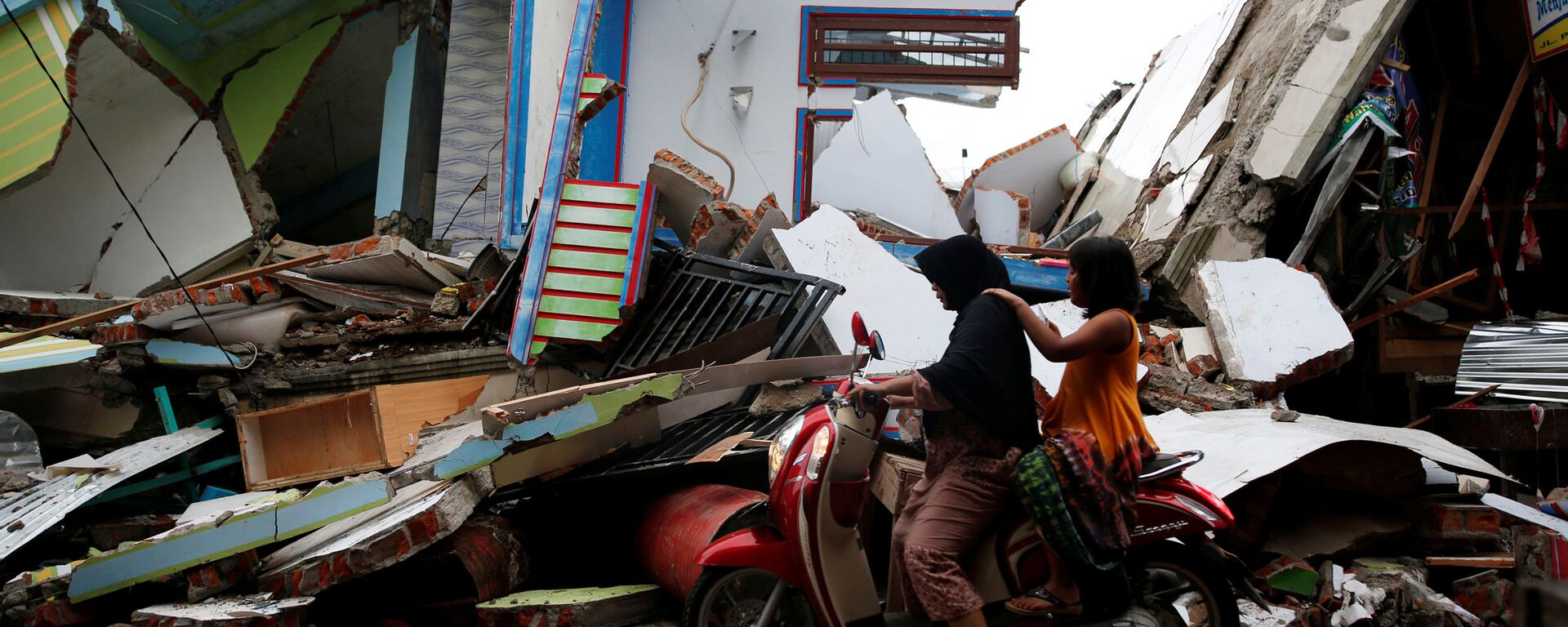 A woman and child ride a motorcycle past damaged buildings following this week's strong earthquake in Meureudu market, Pidie Jaya, Aceh province, Indonesia December 9, 2016. - Sputnik Việt Nam, 1920, 15.03.2017