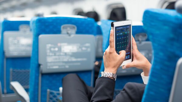Бизнесмен с телефоном в руках в салоне самолета - Sputnik Việt Nam