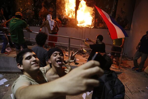 Những người đàn ông chụp ảnh trước tòa nhà Quốc hội trong cuộc đụng độ với cảnh sát sau bầu cử ở Asuncion, Paraguay - Sputnik Việt Nam