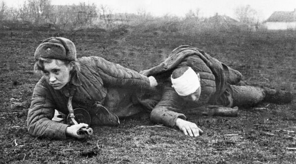 Hướng dẫn viên y tế Valentina Gribkova sơ tán người bị thương khỏi chiến trường. - Sputnik Việt Nam