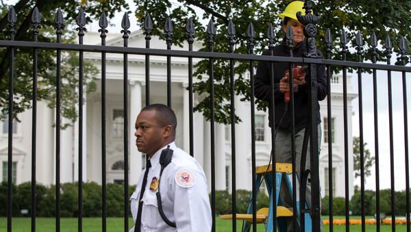 A Secret Service police officer walks outside the White House in Washington, Thursday, Oct. 23, 2014, as a maintenance worker performs fence repairs as part of a previous fence restoration project. - Sputnik Việt Nam