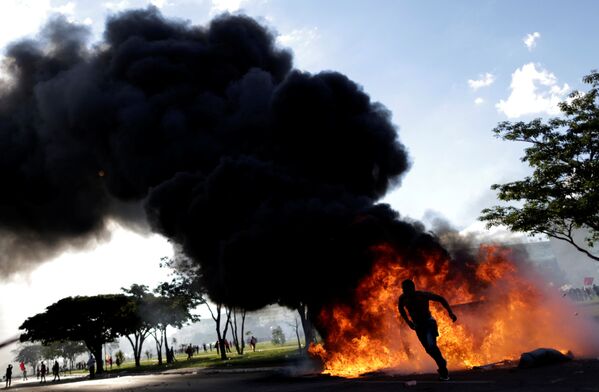 Người biểu tình bên cạnh chướng ngại vật bốc cháy trong cuộc biểu tình phản đối Tổng thống Brazil. - Sputnik Việt Nam