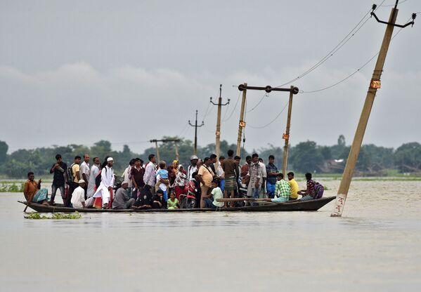 Ấn Độ,  bang Assam. Người dân làng quê địa phương  trong khi vượt qua con đường ngập lụt. - Sputnik Việt Nam