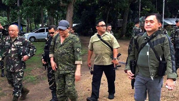 Tổng thống Duterte (đội mũ) mặc quân phục và vác súng trường tấn công trong chuyến đi bất thành đến TP Marawi vào ngày 7-7. - Sputnik Việt Nam