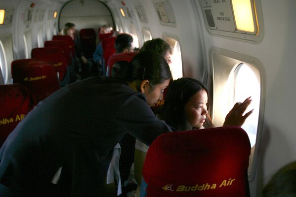 Tiếp viên hãng hàng không Nepal Buddha Air chỉ cho hành khách thấy đỉnh Everest. - Sputnik Việt Nam