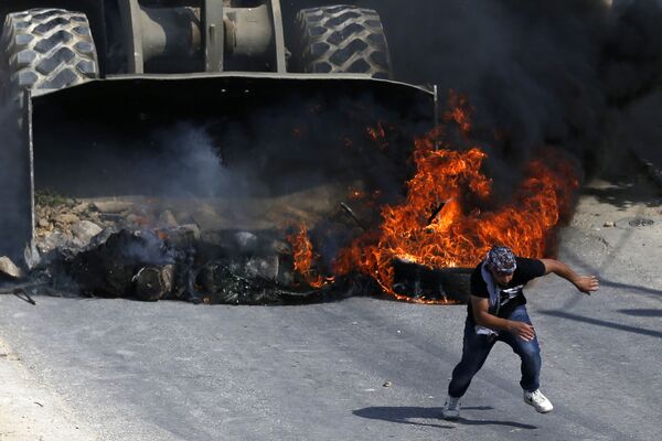 Người Palestine chạy tránh xe ủi của quân đội Israel trong cuộc bạo loạn tại ngôi làng gần thành phố  Ramallah  (Bờ Tây sông Jordan). - Sputnik Việt Nam