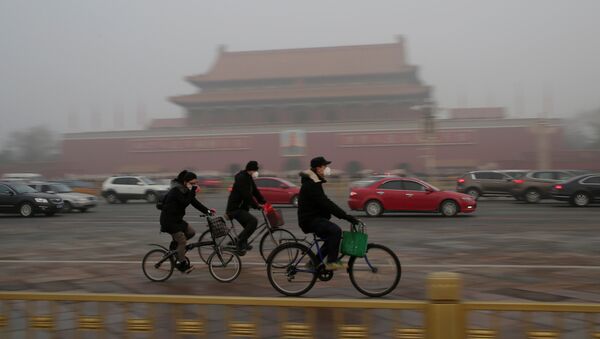 People wearing masks cycle past Tiananmen Gate during the smog after a red alert was issued for heavy air pollution in Beijing, China, December 20, 2016. - Sputnik Việt Nam