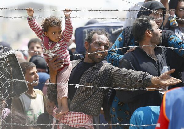Người tị nạn Sirya ôm bé gái trên tay xếp hàng tại biên giới với Thổ Nhĩ Kỳ - Sputnik Việt Nam
