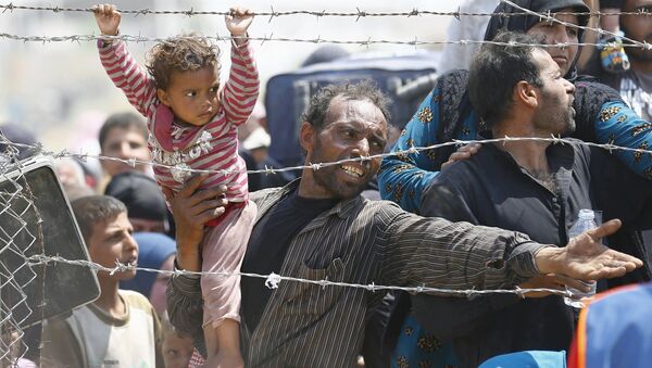 Người tị nạn Sirya ôm bé gái trên tay xếp hàng tại biên giới với Thổ Nhĩ Kỳ - Sputnik Việt Nam
