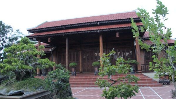 Căn nhà rường gỗ được xây dựng trong khuôn viên vườn, xung quanh bao bởi tường bê tông, có cây cối - Sputnik Việt Nam