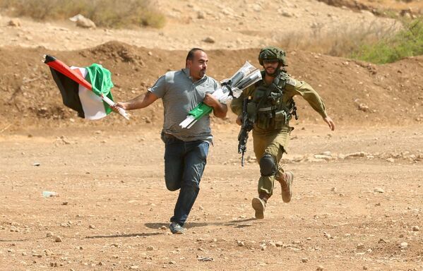 Lính Israel chạy sau một người Palestine trong cuộc đụng độ ở Bờ Tây sông Jordan - Sputnik Việt Nam