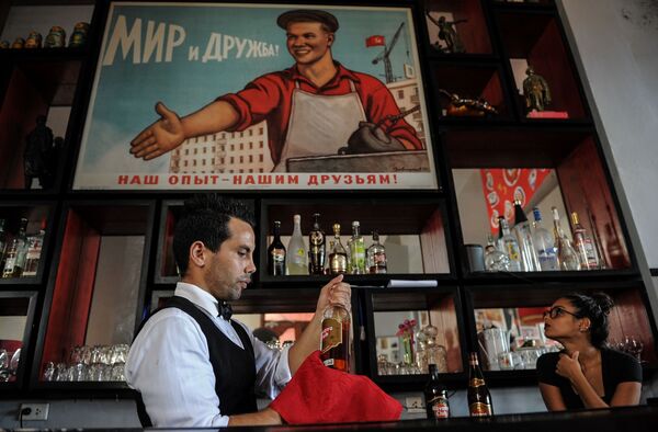 Người phục vụ trong nhà hàng ẩm thực Nga Chúc sức khỏe! ở La Habana trên nền biểu ngữ Liên Xô. - Sputnik Việt Nam