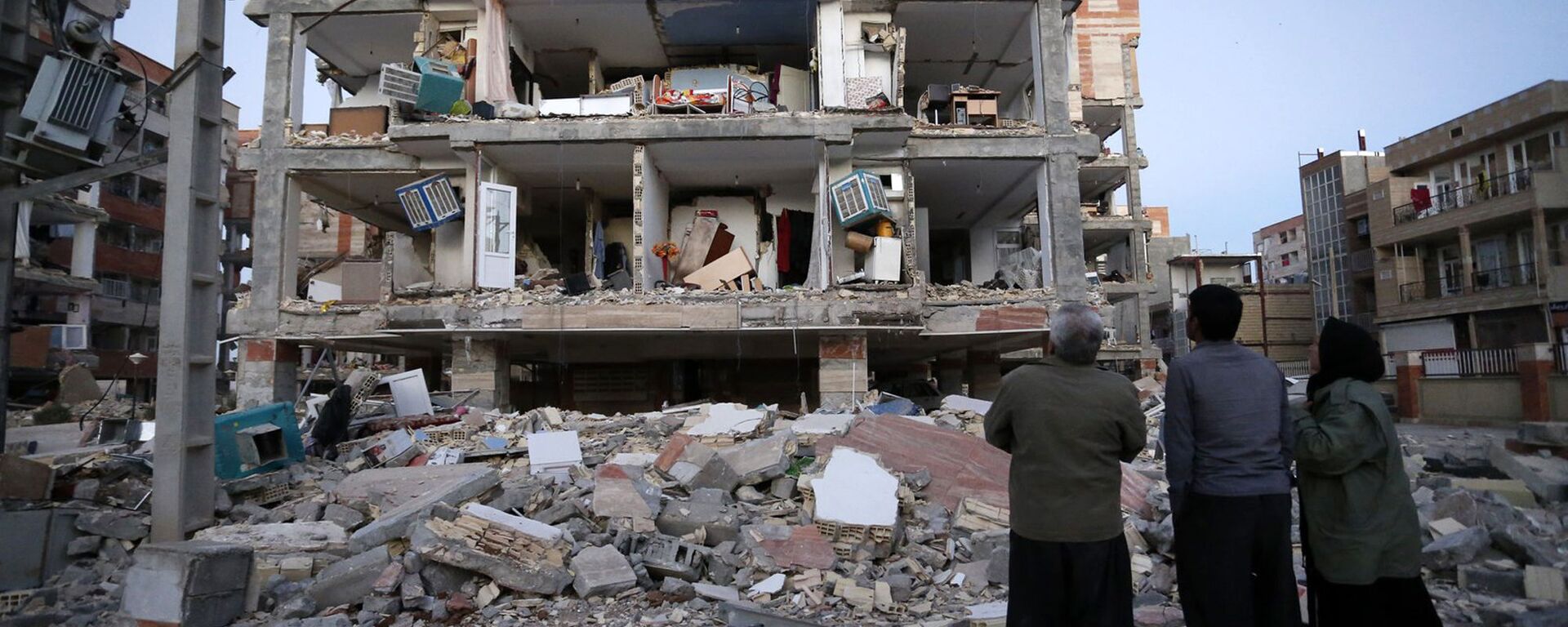 Mọi người nhìn tòa nhà bị động đất phá hủy ở thành phố Sere-Polye Zohab, Iran - Sputnik Việt Nam, 1920, 18.01.2023