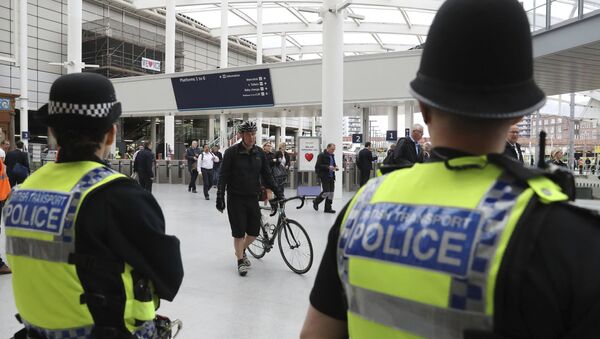 Police watch as commuters pass through Manchester Victoria railway station in Manchester England, which has reopened for the first time since the terror attack on the adjacent Manchester Arena Tuesday May 30, 2017 - Sputnik Việt Nam