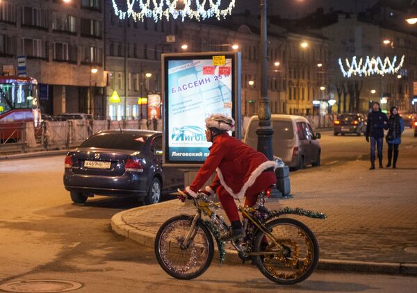 Một người đàn ông trong bộ trang phục Ông già Tuyết đi xe đạp trên đường phố  St. Petersburg - Sputnik Việt Nam