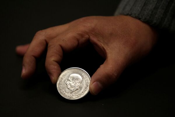 Một người đàn ông cho xem một đồng xu bạc Mexico Hidalgo 5 peso tại  cửa hàng trao đổi tiền tệ ở Ciudad Juarez, Mexico - Sputnik Việt Nam