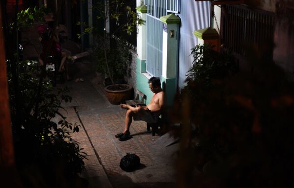Người đàn ông đang ngồi  trước nhà ở thành  phố Hồ Chí Minh, Việt Nam. - Sputnik Việt Nam