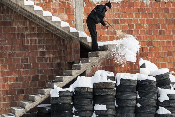 Người đàn ông dọn tuyết từ cầu thang ngôi nhà trong làng Mramor, Pristina, Serbia - Sputnik Việt Nam