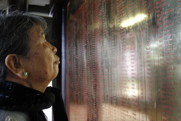 Nữ cư dân địa phương Trương Thị Hồng bên tấm bia ghi tên các nạn nhân của vụ thảm sát Sơn Mỹ, Việt Nam - Sputnik Việt Nam