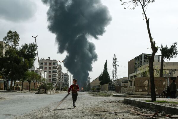 Đứa trẻ chạy trên đường phố trong thành phố Douma sau khi báo động máy bay không kích ở Đông Ghouta, Syria - Sputnik Việt Nam