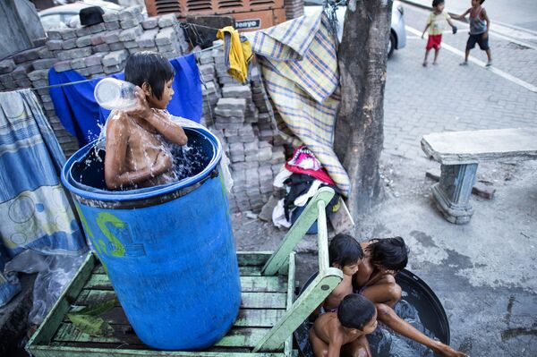 Trẻ em tắm trong thùng trên đường phố Manila - Sputnik Việt Nam