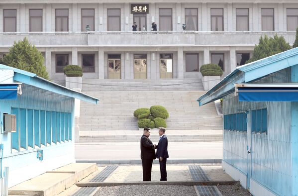 Lãnh tụ Nam-Bắc Triều Tiên Moon Jae-in và Kim Jong-un bắt tay nhau trong cuộc gặp gỡ tại làng Panmunjom, thuộc khu phi quân sự phân chia hai miền Bắc-Nam Triều Tiên. - Sputnik Việt Nam